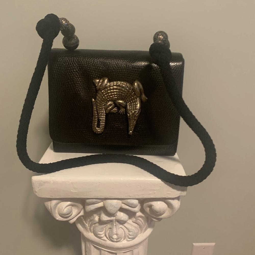 Black handbag with an alligator embellishment.
